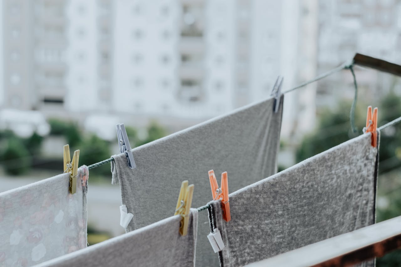 Clothes and towels on a clothesline with clothespins, blurred cityscape background.