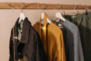 Close-up of fashionable clothes hanging on a wooden rack with string lights.