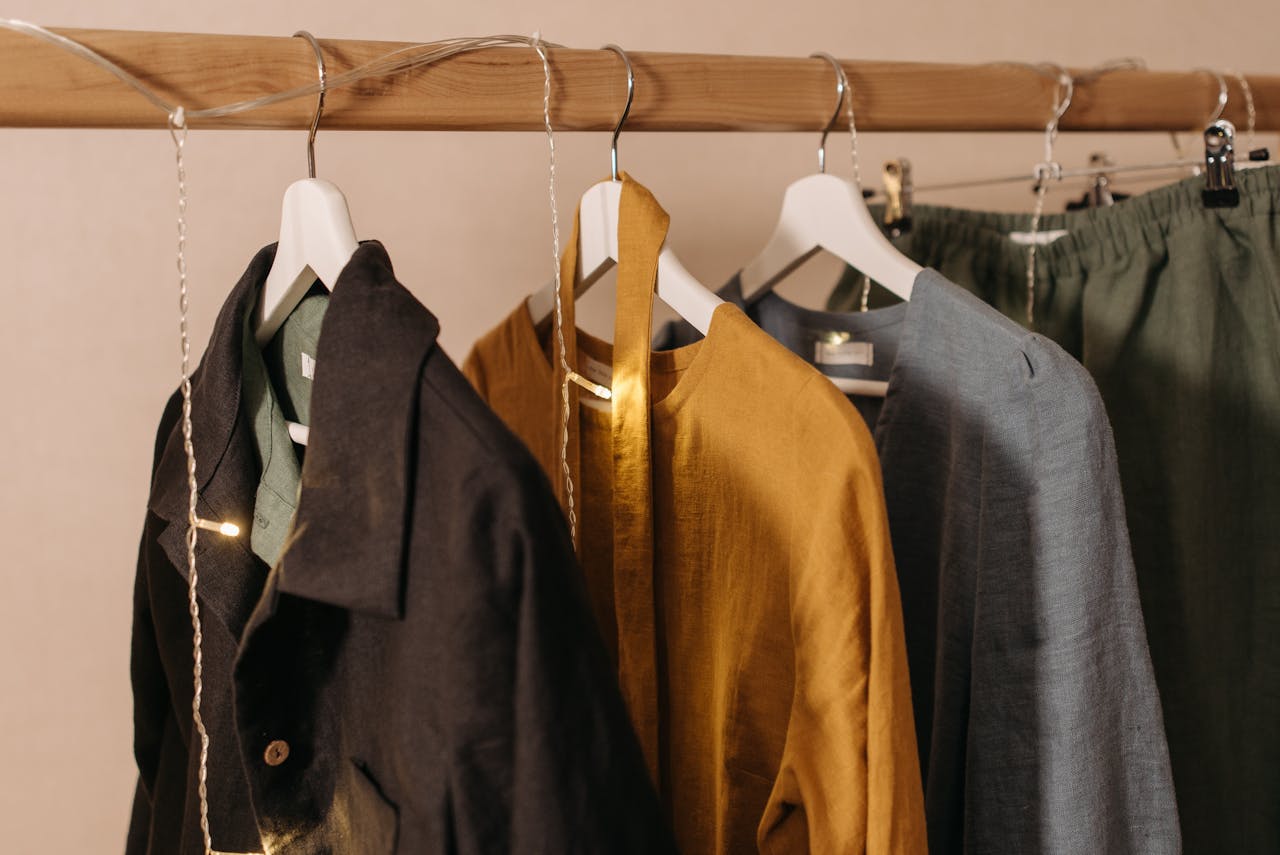Close-up of fashionable clothes hanging on a wooden rack with string lights.